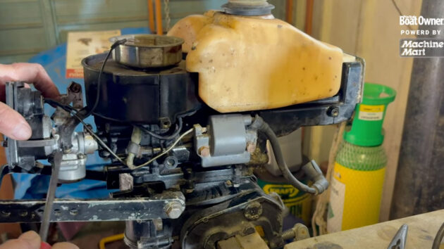A person servicing a two-stroke outboard engine