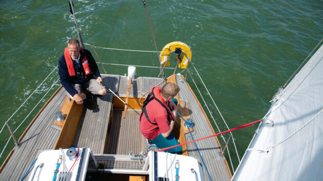 Two men wearing lifejackets sailing