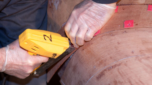 A man applying staples to the hull of a boat