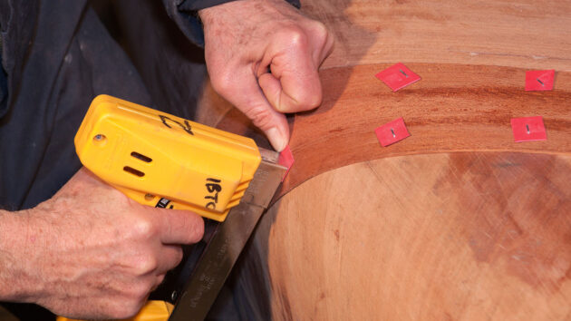 a man using a staple gun to fix veneer ply to cold moulding hull