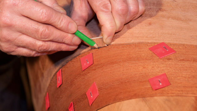 A man marking a piece of wood during boat building