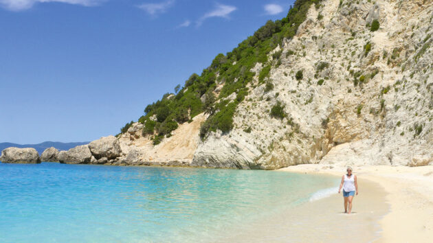 A woman walking along a beach in Greece