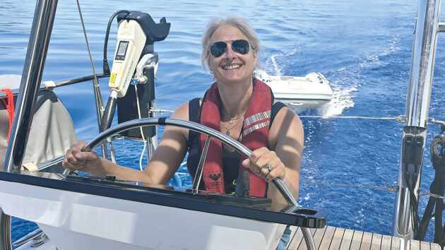 A woman at the helm of a yacht during a charter holiday in Greece