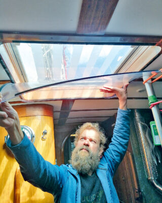 A man installing temporary glazing on a boat to control condensation and damp