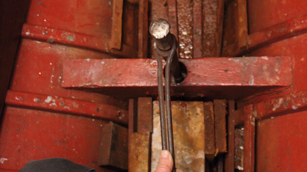 A hammer being used as part of inspecting and replacing keel bolts on a boat