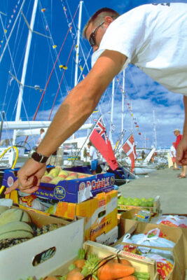 A man sorting through boxes of fruit and vegetable on a quayside