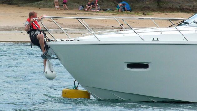 mooring your boat: a man trying to pass a line through the ring of a mooring buoy