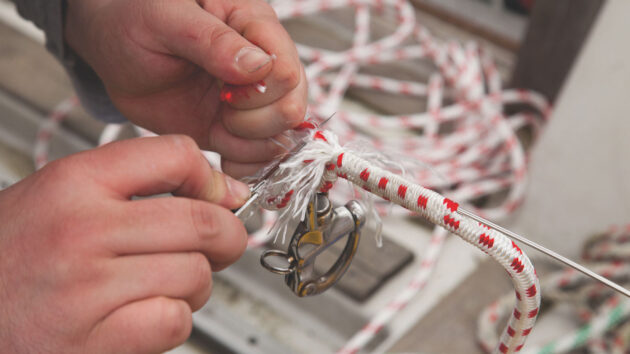 A man splicing a shackle onto running rigging