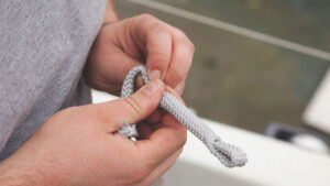 A man preparing rope for running rigging replacement on a boat