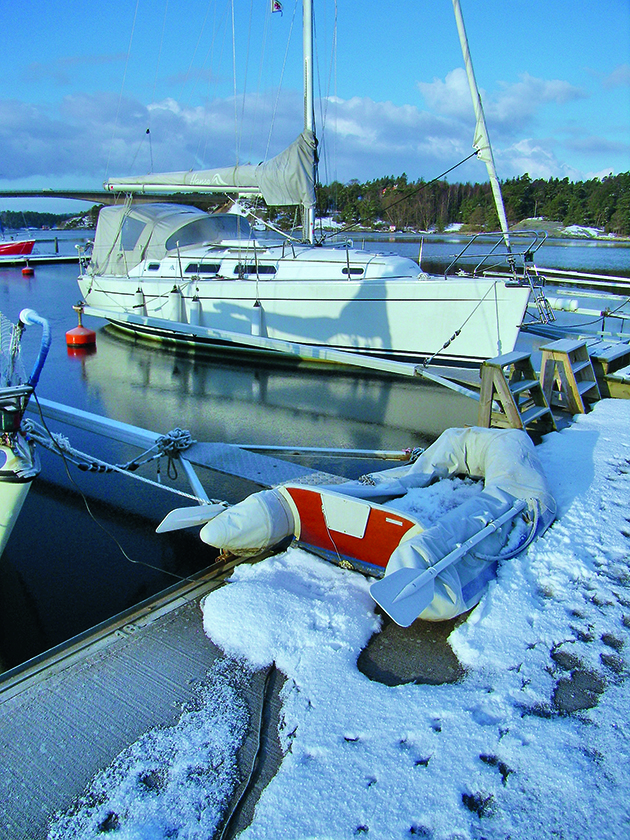 Boat on the water with snow on the pontoon. 
