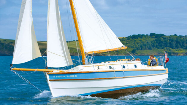 A boat with a blue and white hull and white sails