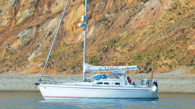 A boat at anchor by a cliff