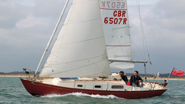 Two men sailing a yacht with slab reefing