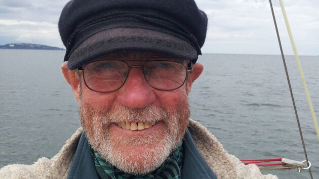 A man smiling wearing a black cap