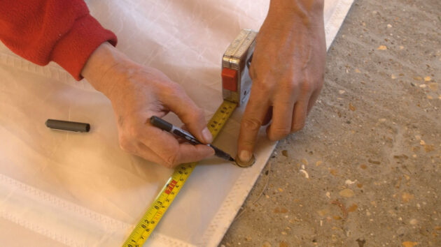 A man measuring sail cloth for reefing points
