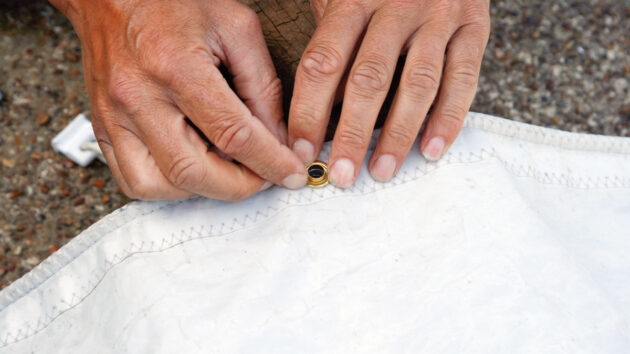 An eyelet being fitted to a sail