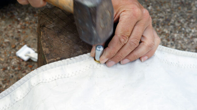 A punch being used to fit an eyelet on a sail