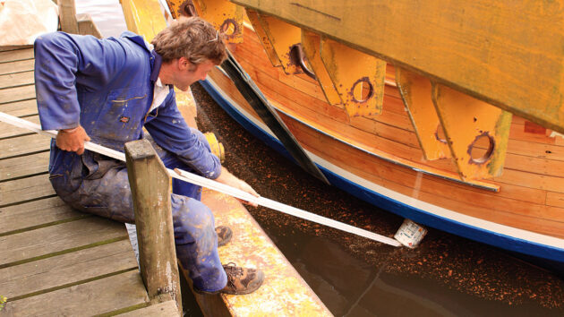 A man doing work on a wooden boat