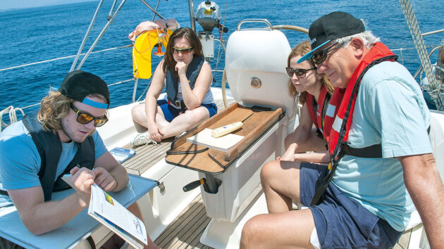 Sailors being taught in the cockpit of a boat