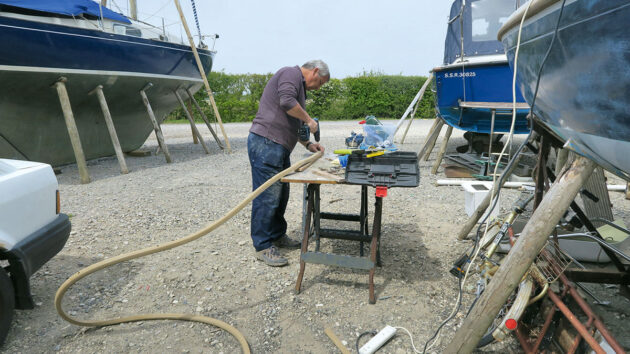 A man drilling holes in PVC gunwale