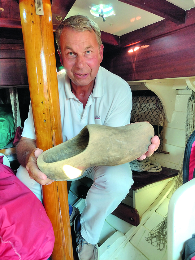A man holding a wooden clog onboard a boat