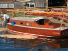 A man pushing sawdust around a boat to help stem leaks on a wooden boat