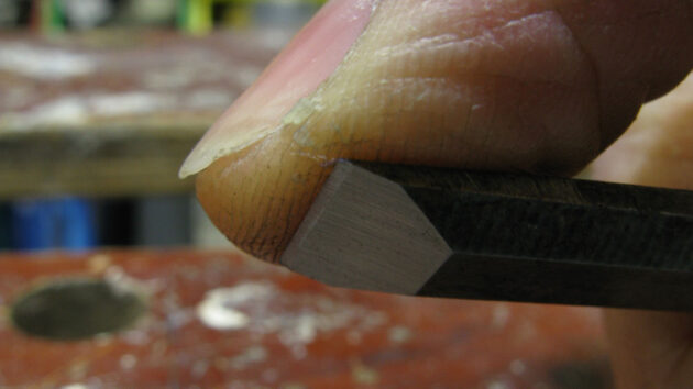 A man testing the sharpness of a chisel