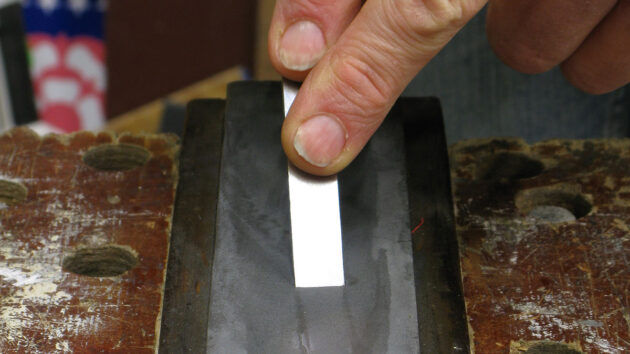 A man showing how to sharpen a chisel on an oilstone