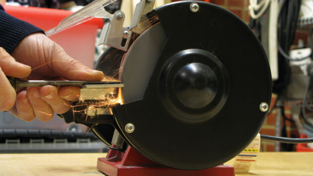 A man grinding the end of a chisel