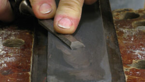 A man who is demonstrating how to sharpen a chisel