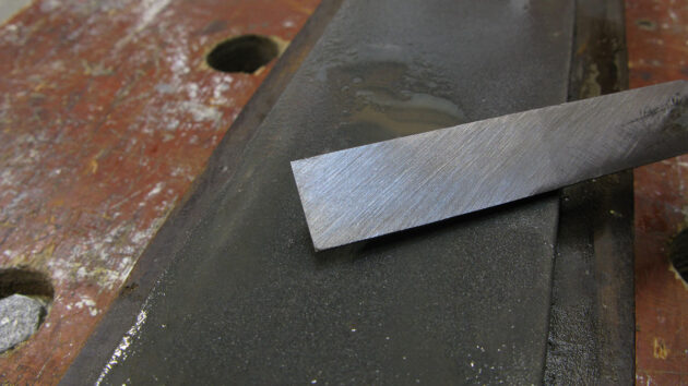 A man showing how to sharpen a chisel on an oilstone