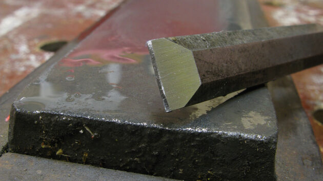 A man showing how to sharpen a chisel on an oilstone