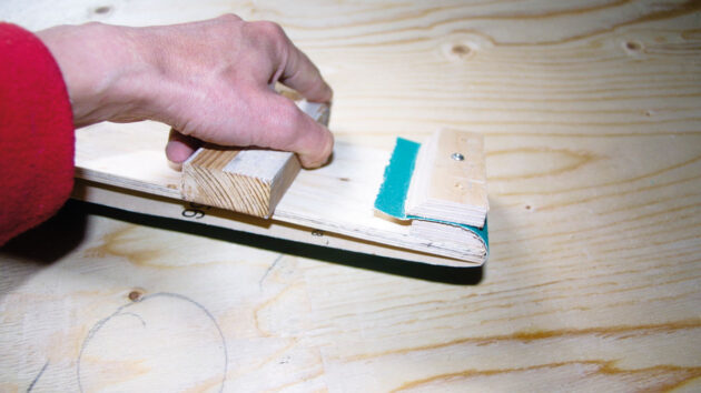 A man making a longboard for sanding on a boat