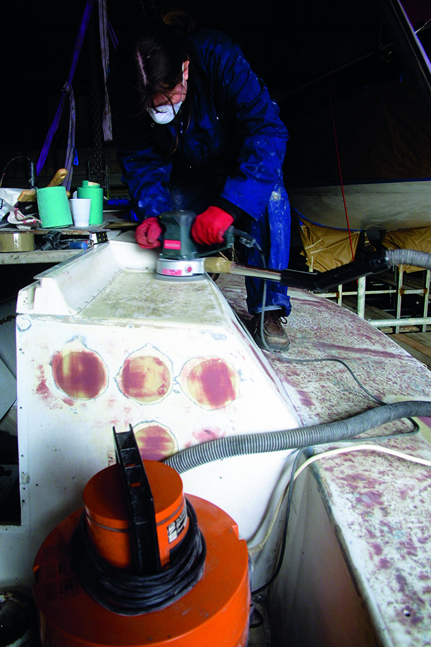 A person sanding plywood decks of a boat