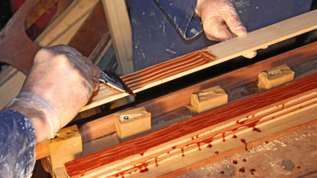 A man laminating wood to make a tiller for a boat