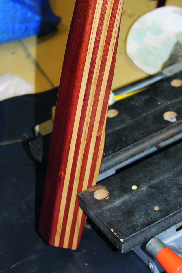 A man varnishing a tiller for a boat