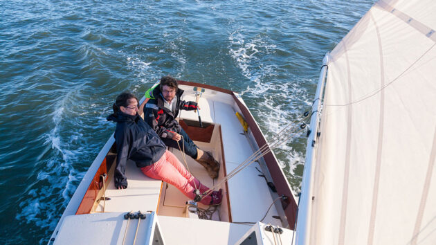 Two people sitting in the cockpit of a boat