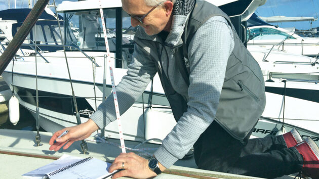 A sailmaker measuring on a boat
