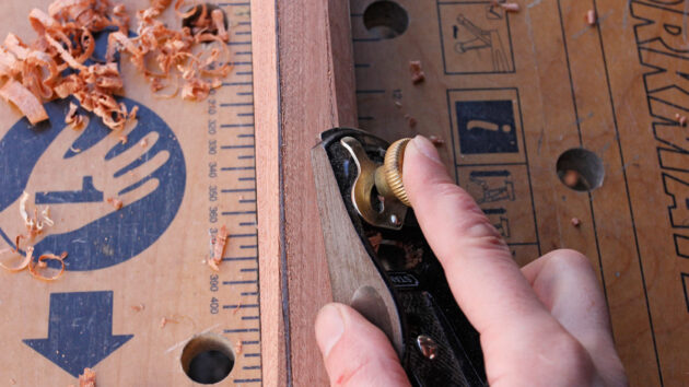 A man using a plane while making a tiller for a boat