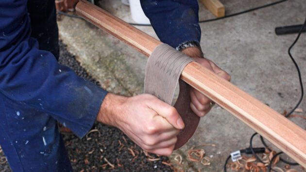 A man sanding a tiller for a boat