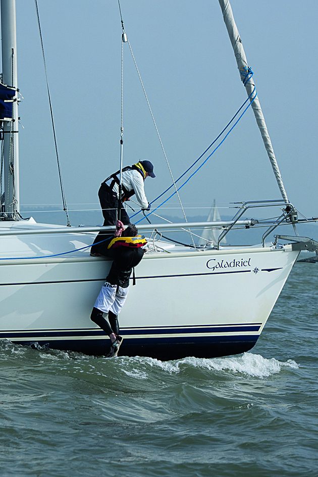 A woman winching up a man from the sea onto the deck of a boat