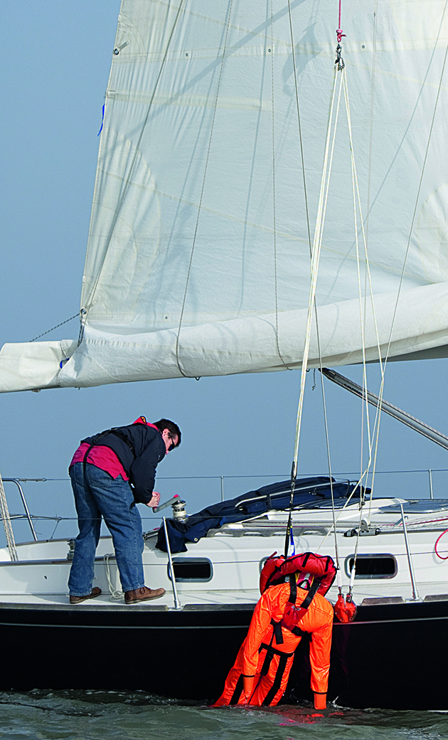 A man using a winch to recover a dummy onto a yacht