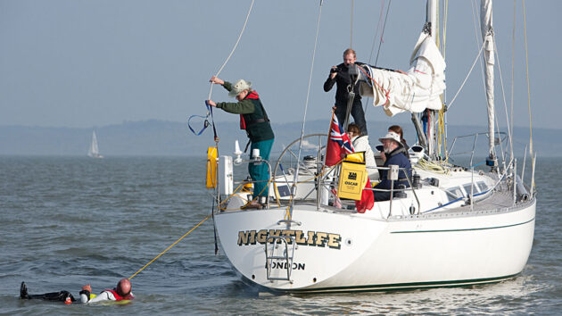 A woman throwing a MOB device to a man in the water