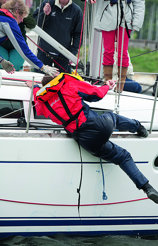 A man wearing a lifejacket being recovered onto a yacht as part of MOB recovery