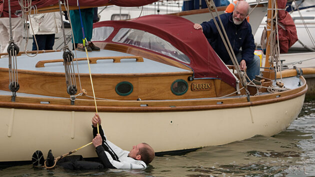 A man in the water by a boat demonstrated MOB recovery