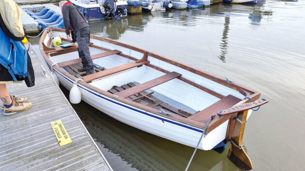 A man standing in a boat by a wooden pontoon