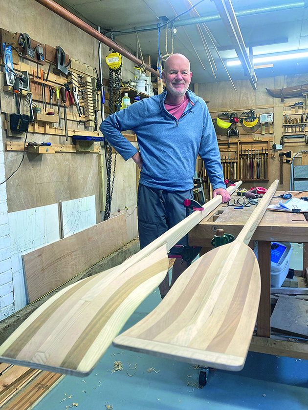 A man standing by two wooden oars