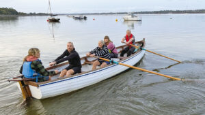 Men and women rowing a salmon seiner on an estuary