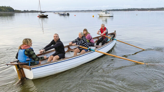 Men and women rowing a salmon seiner on an estuary
