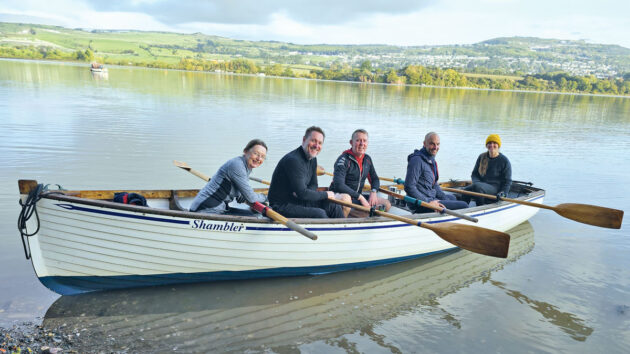 Men and women rowing in a seiner on an estuary